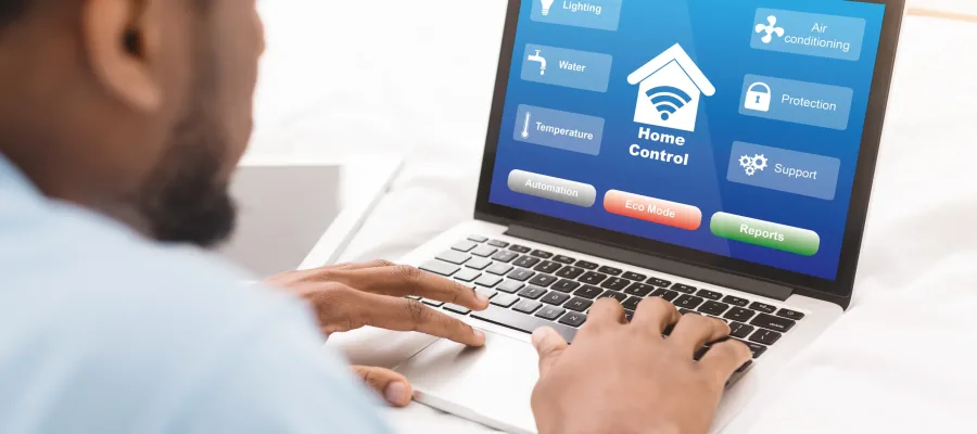 Black Man Using Laptop With Smart Home Control System On Screen, Enjoying Innovative Modern Technologies For House Processes Automation, Lying On Bed In Room, Over Shoulder View, Creative Collage